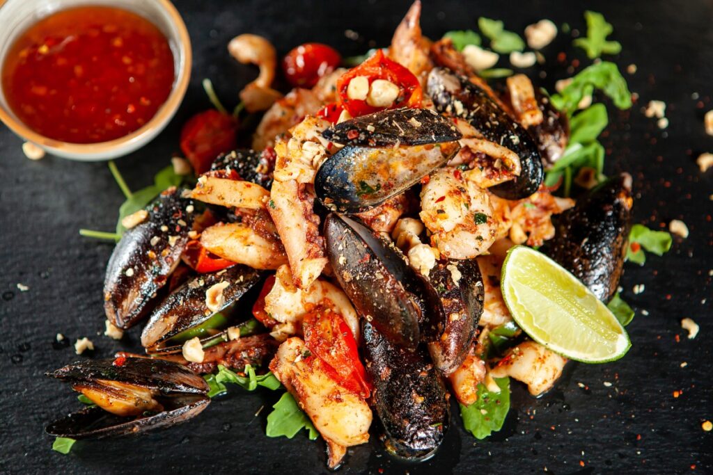 Mediterranean seafood platter with mussels, prawns, lobster, herbs, lime wedge and spicy dipping sauce